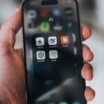Hand holding a phone with ai application icons.