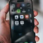 Hand holding a phone with ai application icons.